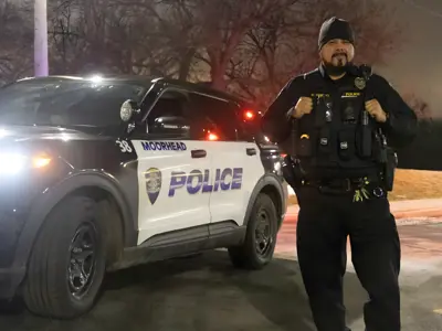 Officer Griego standing outside his squad car at night