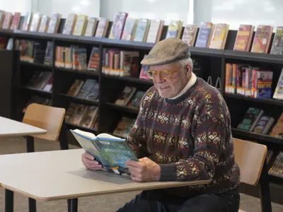 A man sitting and reading a book at a table
