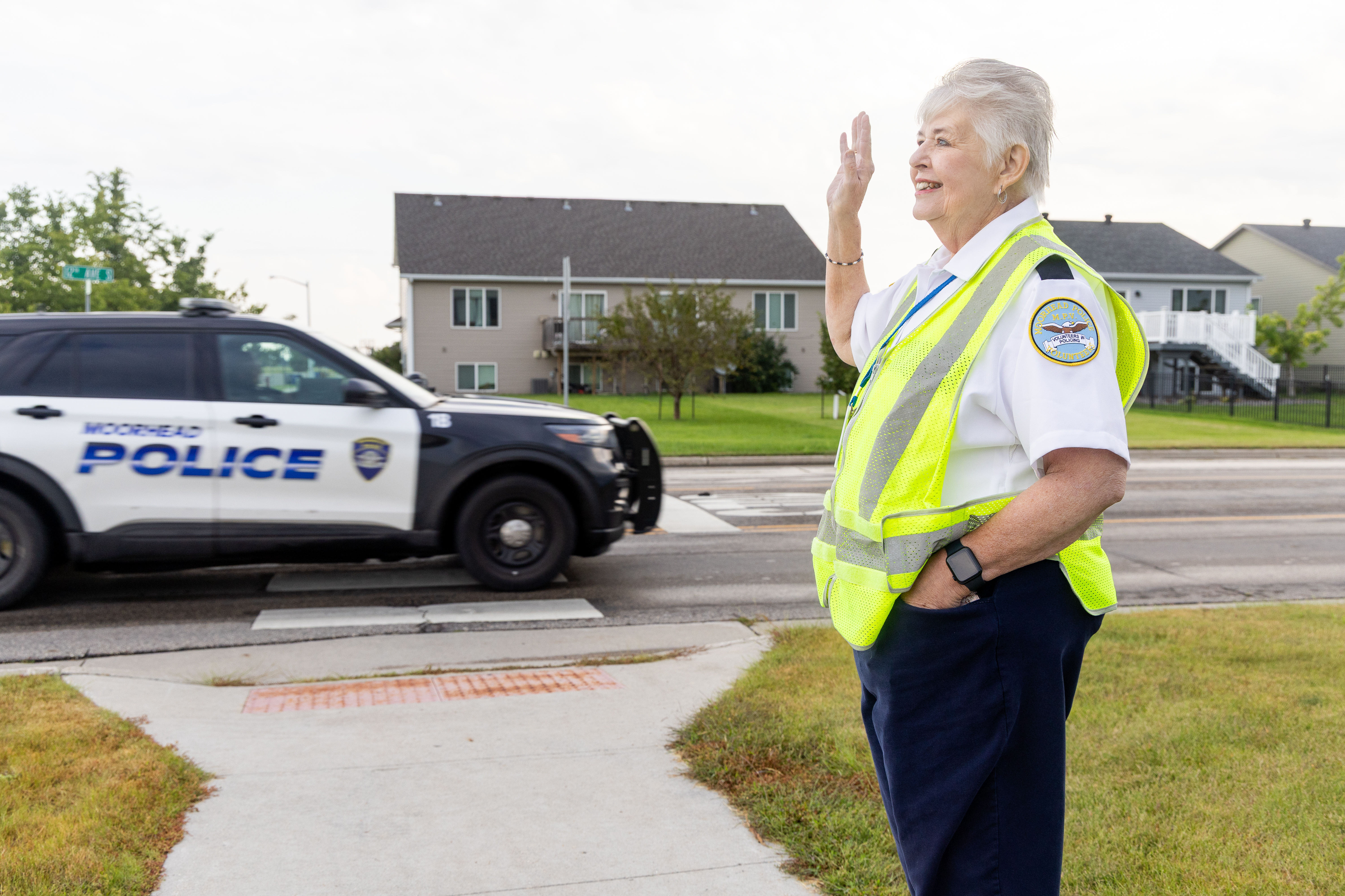 a police volunteer waves to a police car