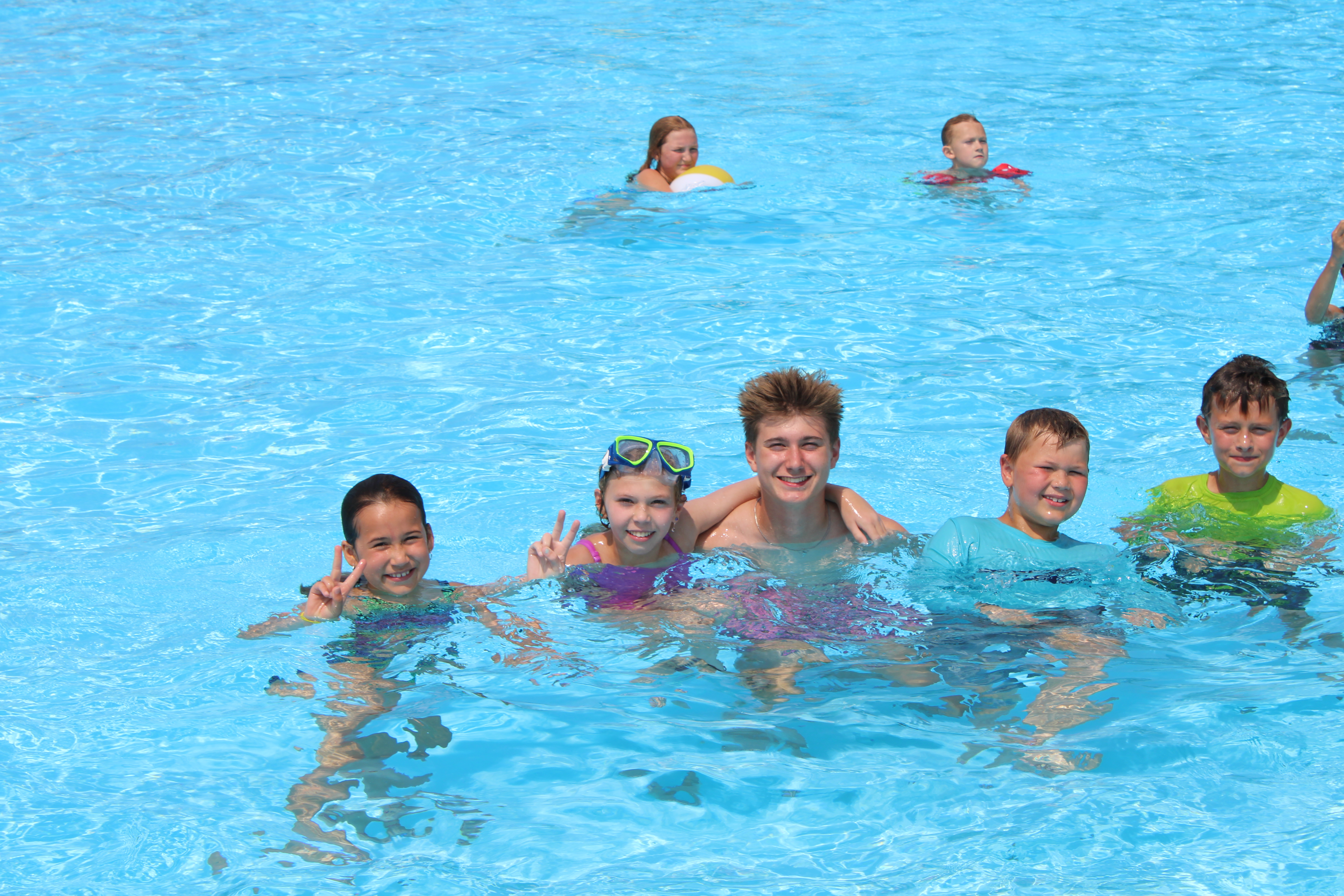 A photo of kids swimming in the pool smiling
