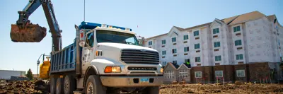 a truck loads dirt into it's back at a construction site