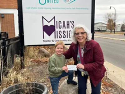 Pastor Sue Koesterman posing with a child in front of a sign