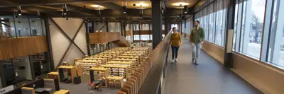 Two people walk on the walking track with the 1st floor of the library in the frame as well