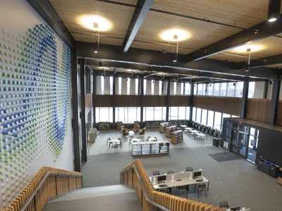 A view from the staircase at the Loop which shows the bookshelves on the first floor along with a mural on the wall