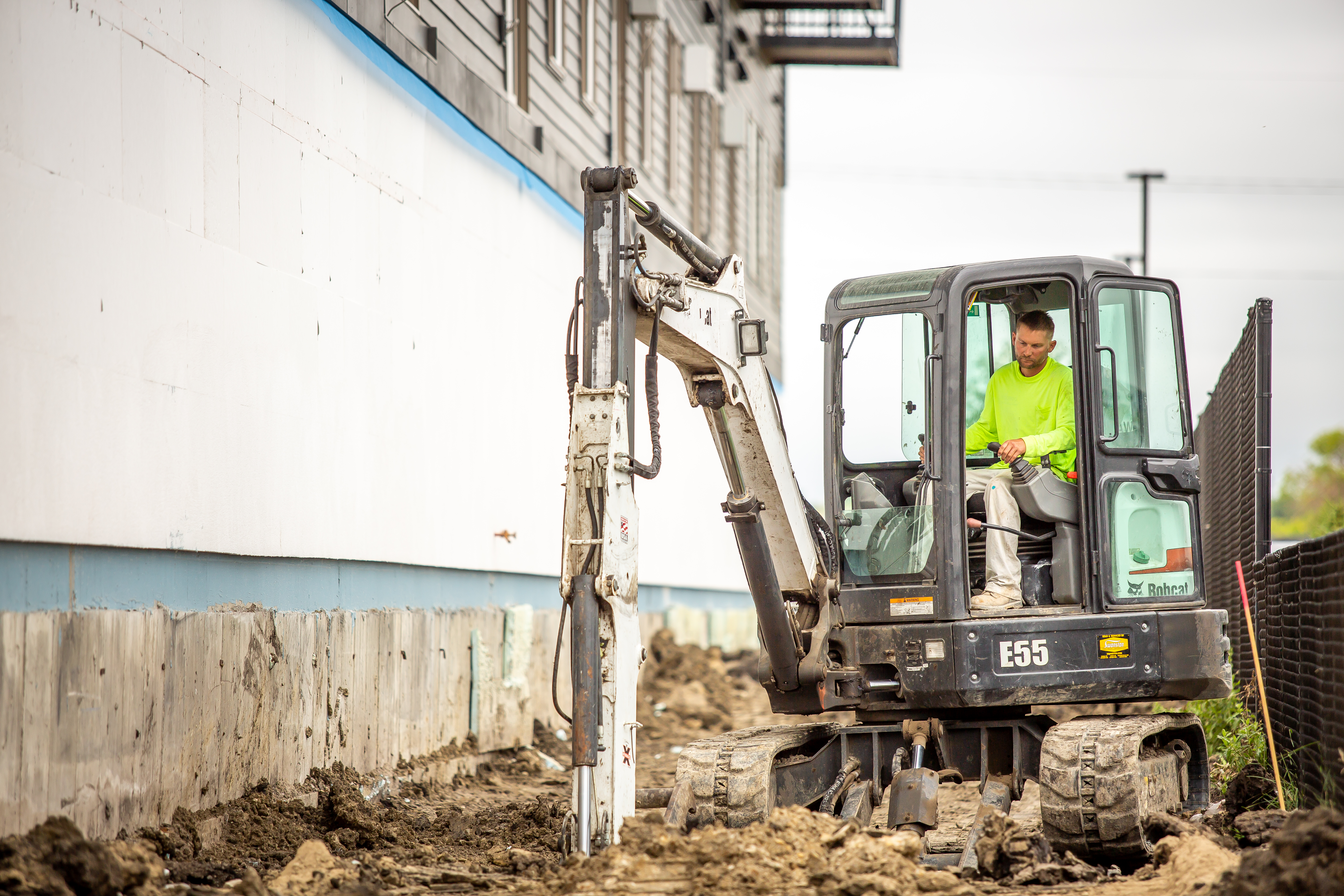 A small machine digs up at a construction site