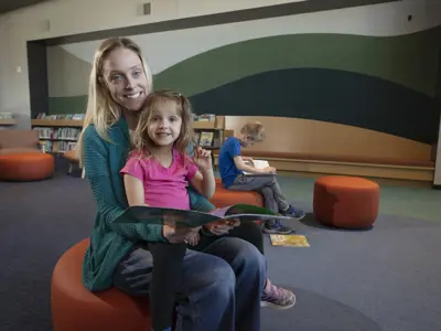 A mom and child in the children's library, reading a book